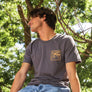 man sitting on a parking structure wall wearing a Bear Hole Monoline shirt from Upper Park Clothing