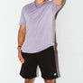 mean leaning against a white wall wearing a orchid simple mineral washed shirt and black men's stadium shorts from Upper Park Clothing