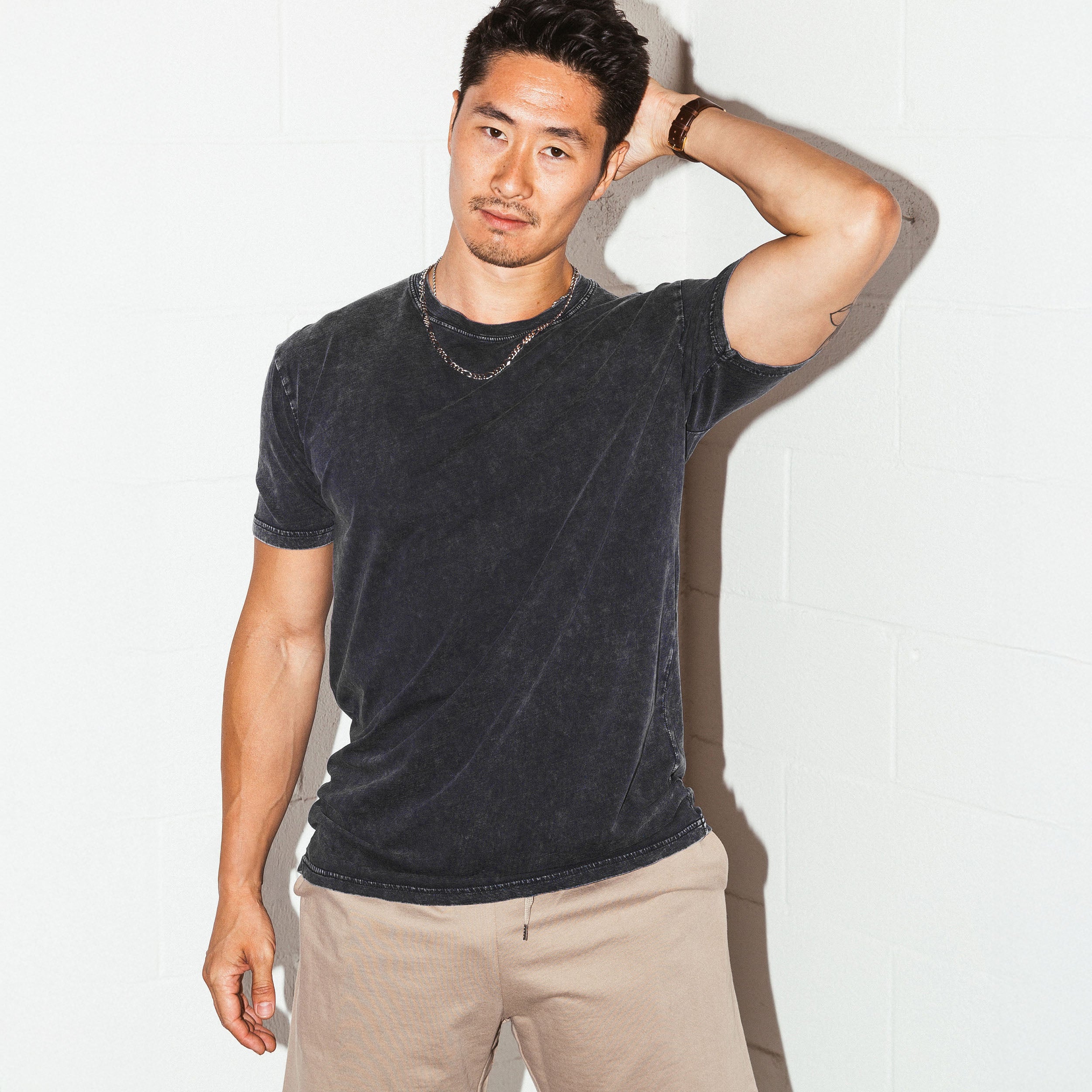 Man wearing a dark gray t-shirt and beige pants against a white background - Upper Park Simple Stone Wash Tee