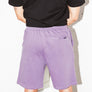 mean leaning against a white wall wearing a black pocket flag and purple stadium shorts from Upper Park Clothing