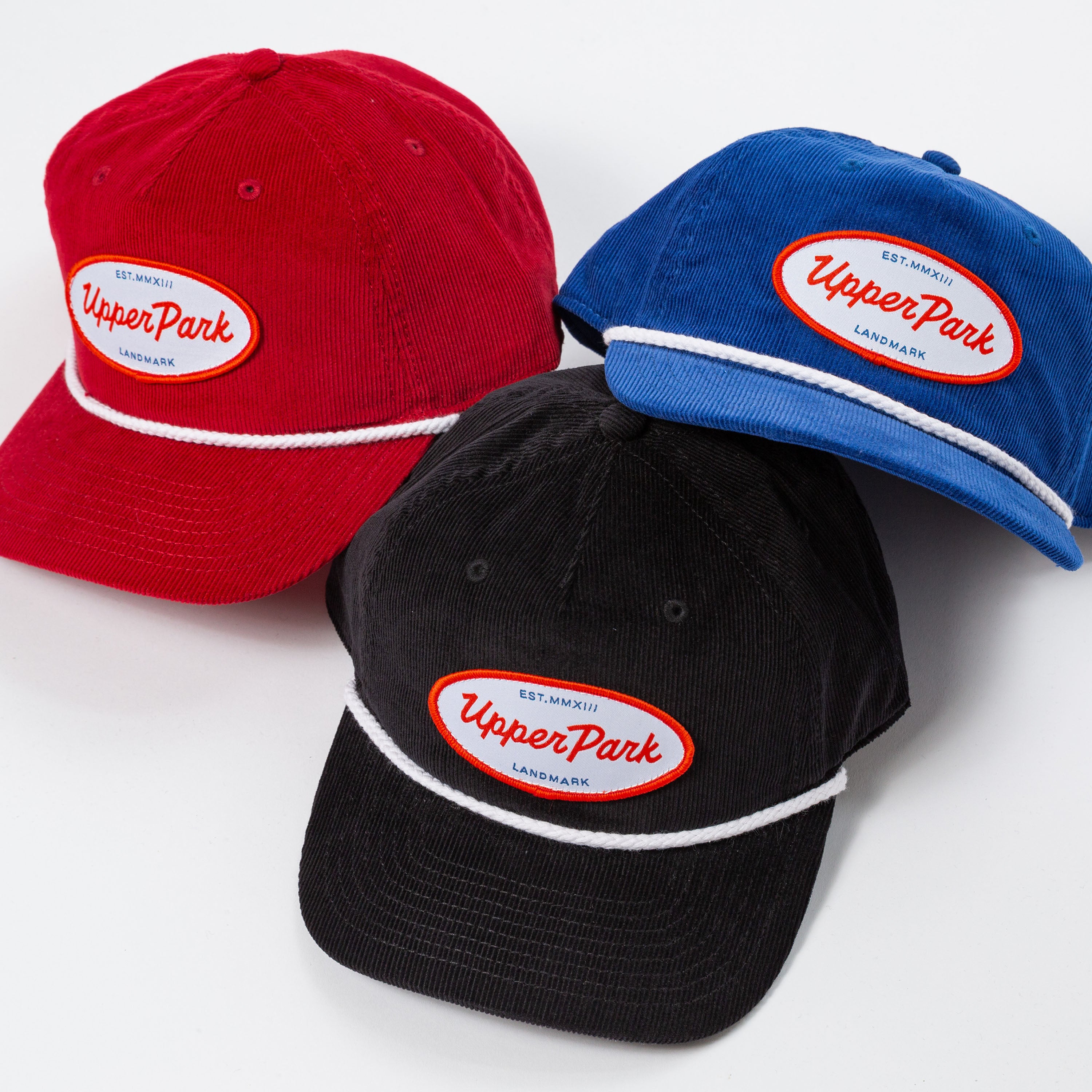 Three baseball caps in red, black, and blue with 'Upper Park' logo on a white background - Values Corduroy Rope Hat