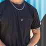 mean leaning against a painted wall wearing a black pocket flag tee from Upper Park Clothing