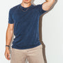 mean leaning against a white wall wearing a blue simple washed mineral tee from Upper Park Clothing