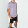 mean leaning against a white wall wearing a orchid simple mineral washed shirt and black men's stadium shorts from Upper Park Clothing