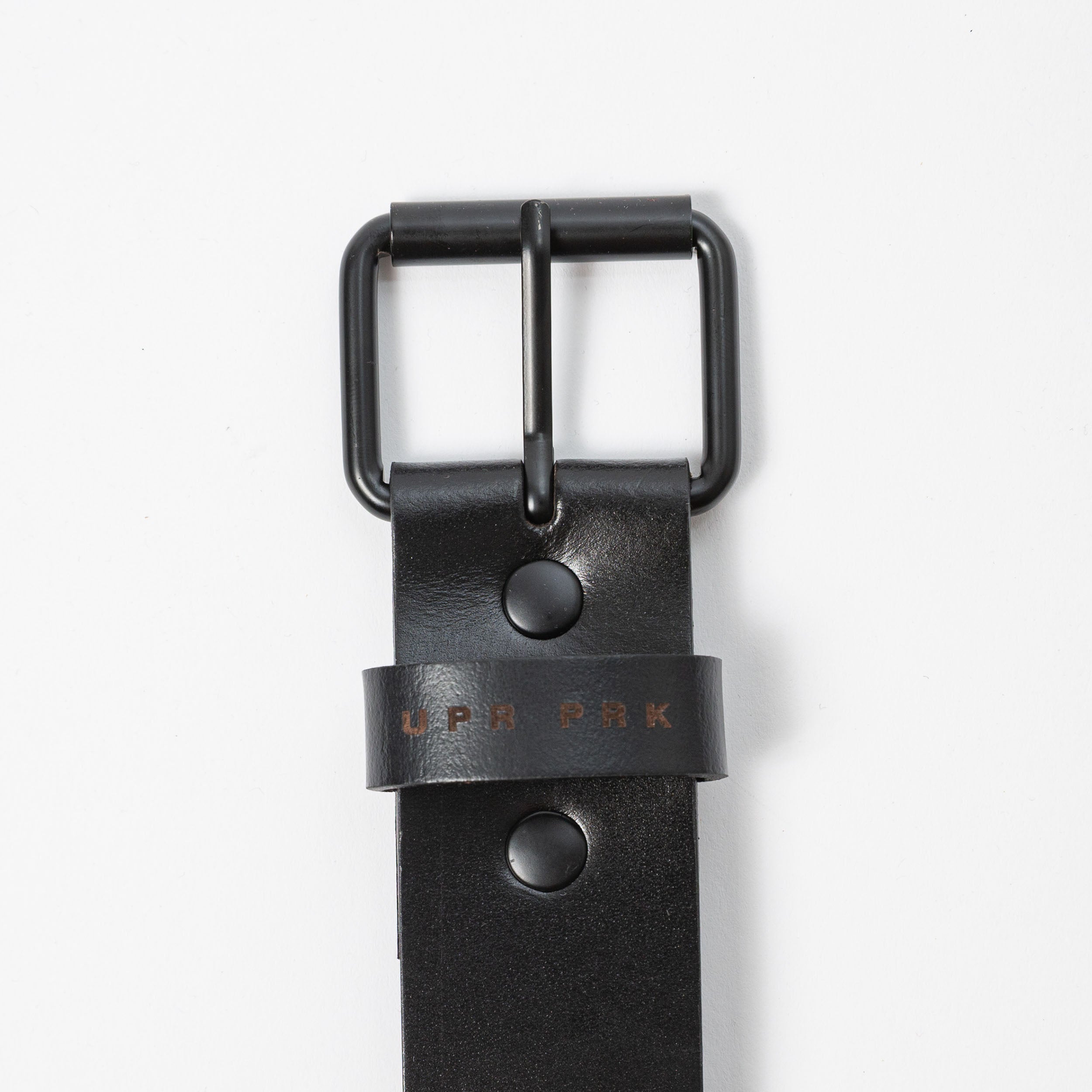 black leather belt with black metal belt buckle on a white background - UPR PRK etched into the leather - Upper Park Basic Leather Belt