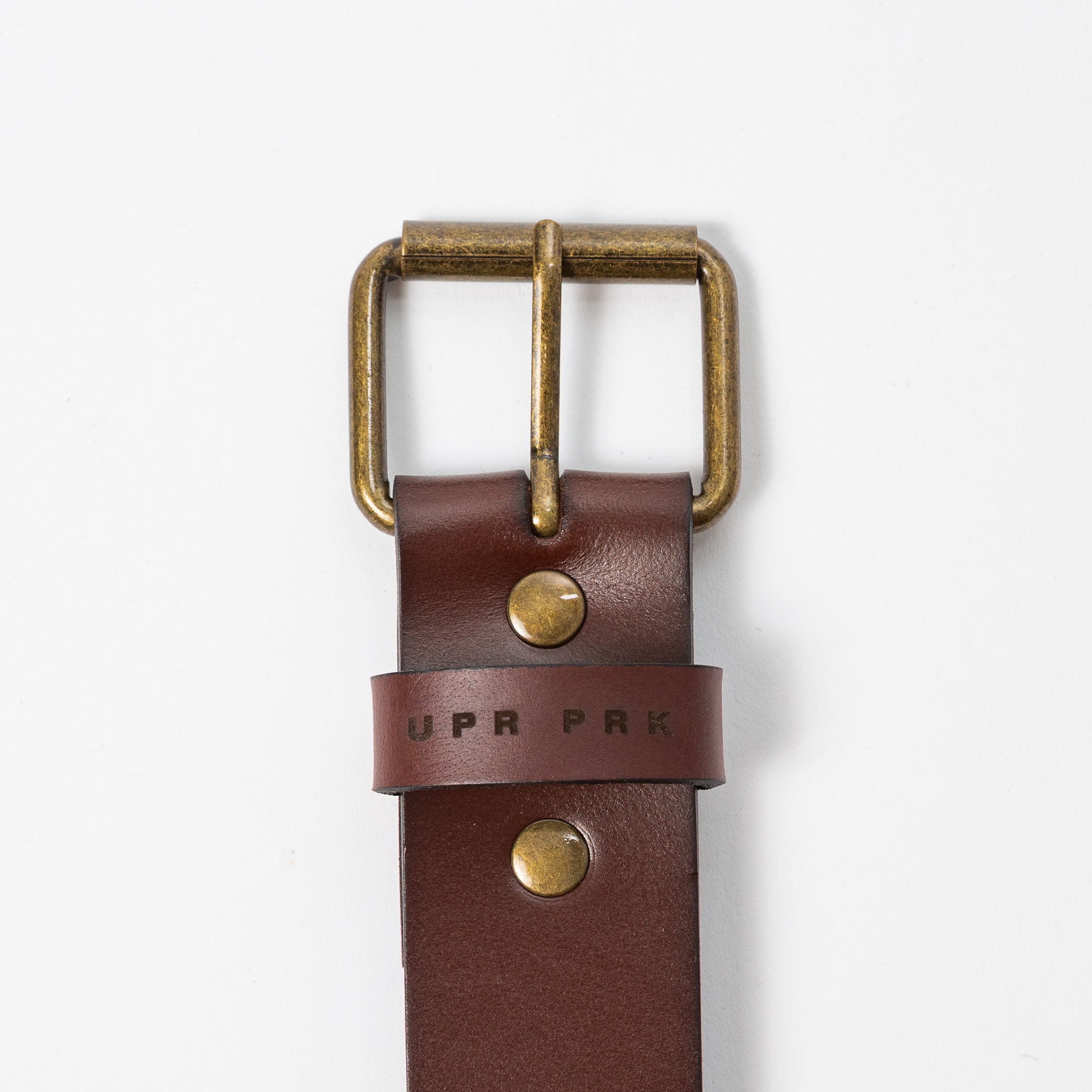 brown leather belt with brass metal belt buckle on a white background - UPR PRK etched into the leather - Upper Park Basic Leather Belt