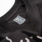 Upper Park Bay Waves Organic Cotton Long Sleeve shirt - Close-up of a black garment with a label on a white background