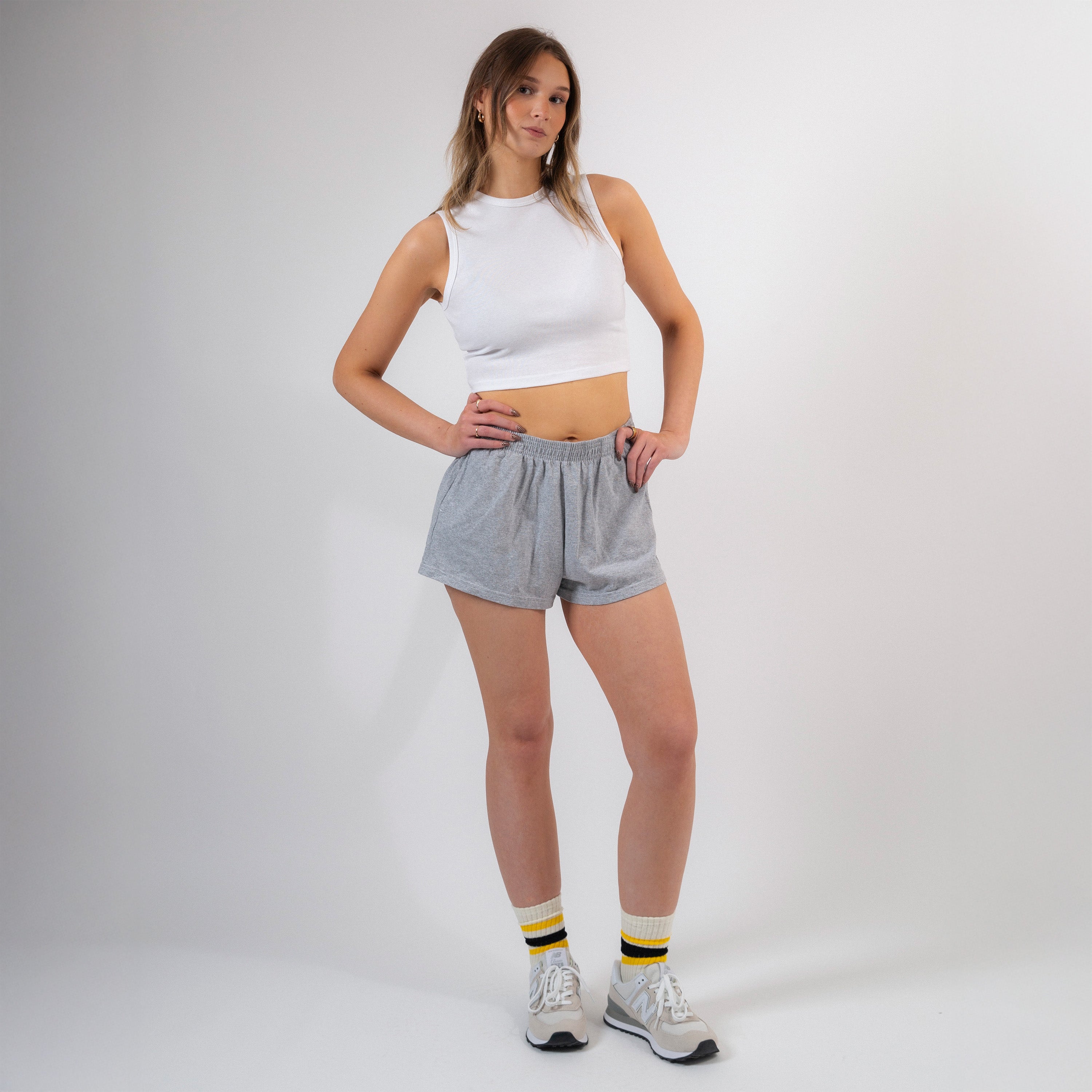 Woman wearing a white tank top and gray shorts on a plain background - Cotton Gym Shorts