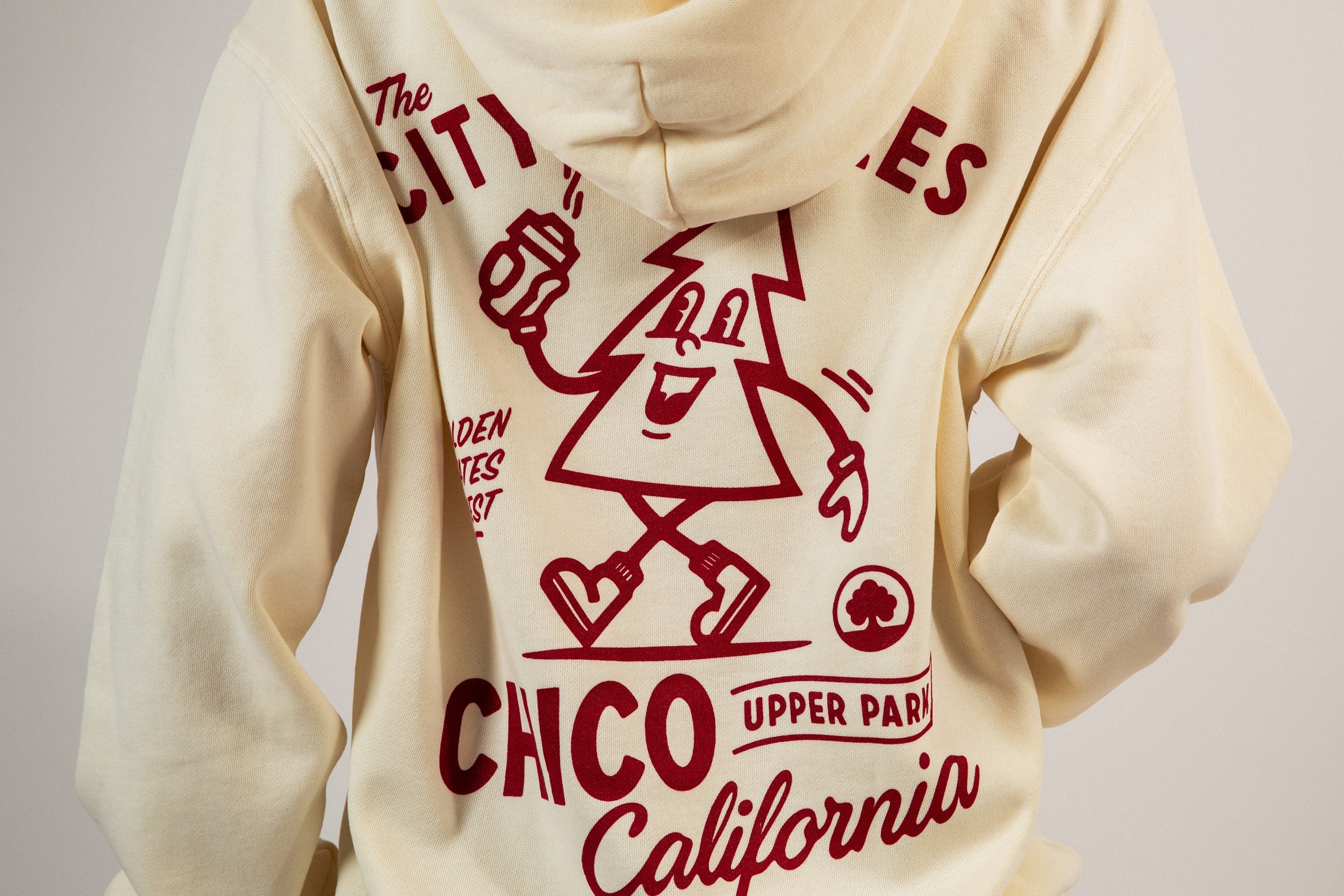 man sitting on a set of stairs in front of MONCA building in Downtown Chico wearing a Corner Store Connoisseurs Hoodie from Upper Park Clothing