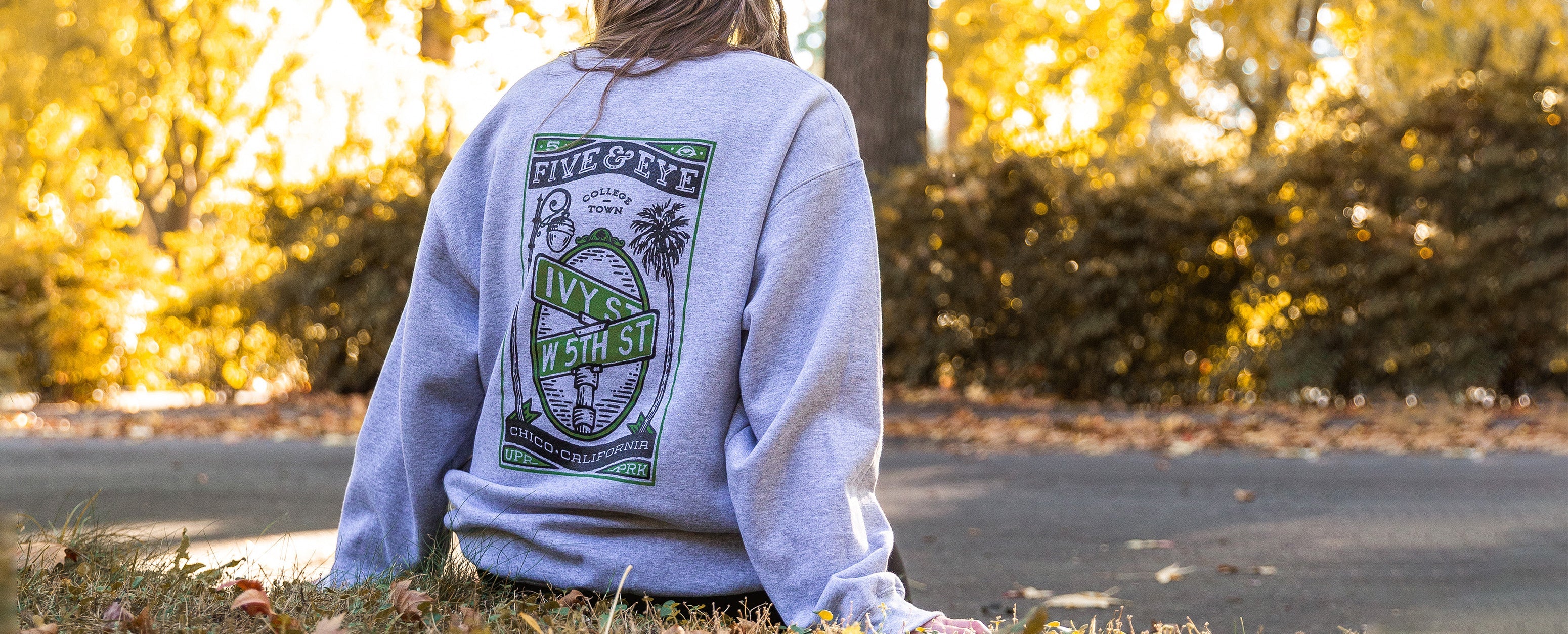 Woman sitting on sidewalk on Esplanade in Chico CA wearing 5th and Ivy sweater