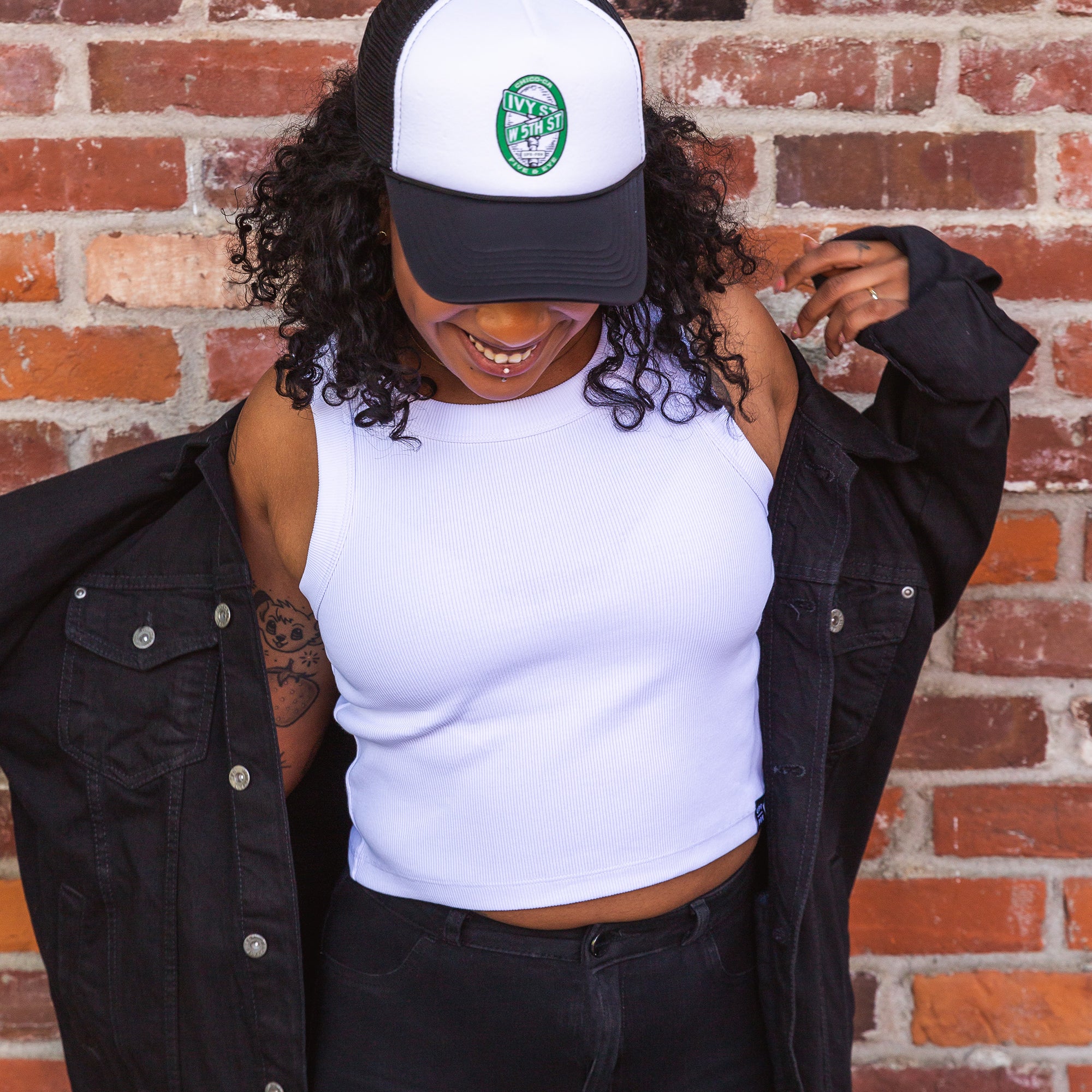 women standing in front of a brick wall wearing a Black Foam Trucker Five and Eye hat from Upper Park Clothing
