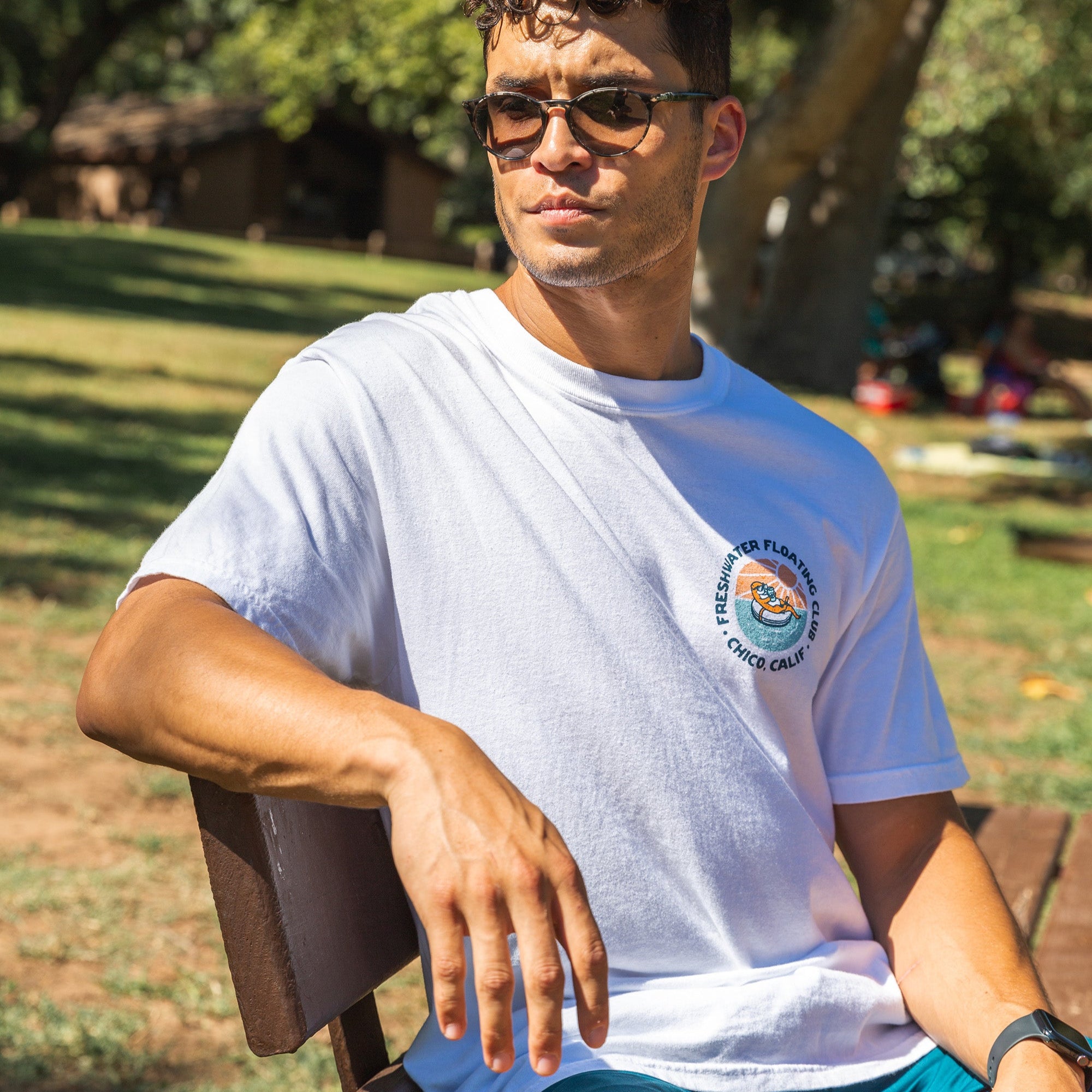 Man sitting on a bench at One Mile swimming pool wearing a Freshwater Floating Club Washed Tee from Upper Park Clothing in Chico, Ca