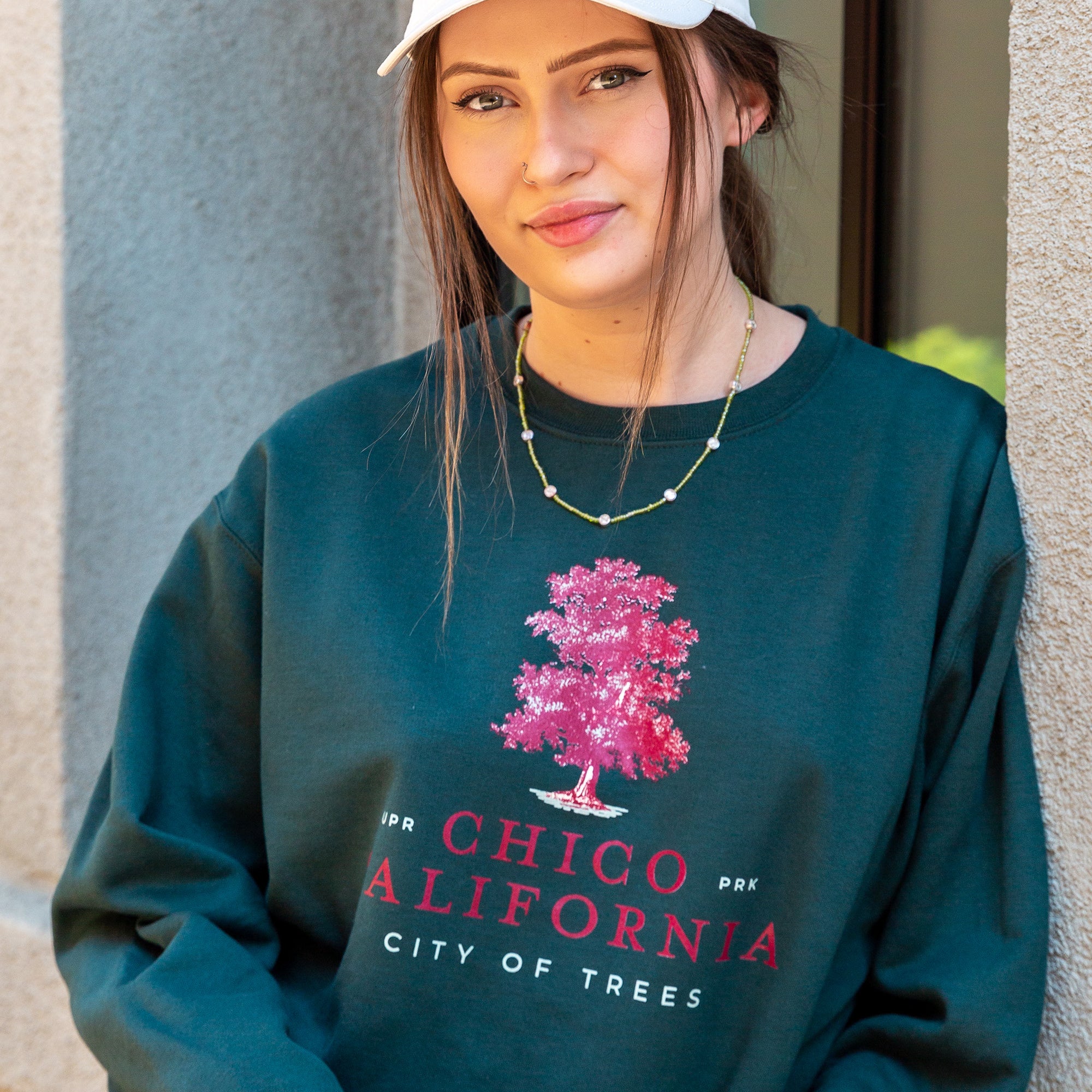 women standing next to Hotel Diamond in Downtown Chico wearing a Chico City of Trees Thrifty Crew Neck Sweater and a Amanita Mushroom hat from Upper Park Clothing