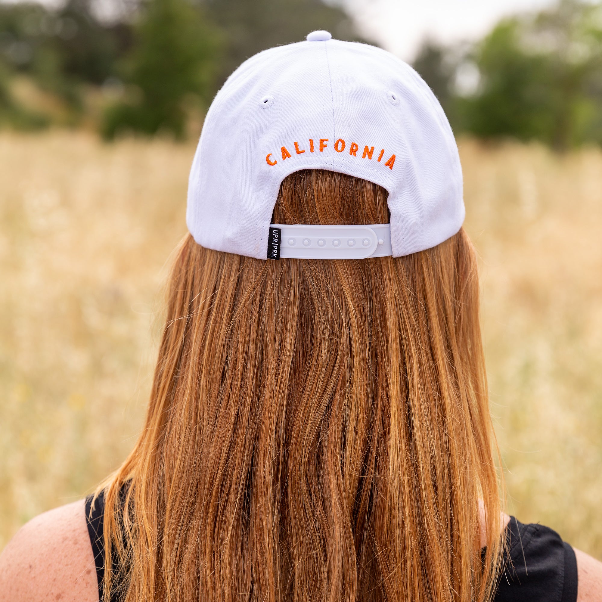 a women sitting and wearing a Upper Park Clothing California Poppy White Hat in Upper Bidwell Park Chico