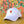a white California Poppy Hat from Upper Park Clothing sitting on a table in front of a Orange wall with some flowers painted on it