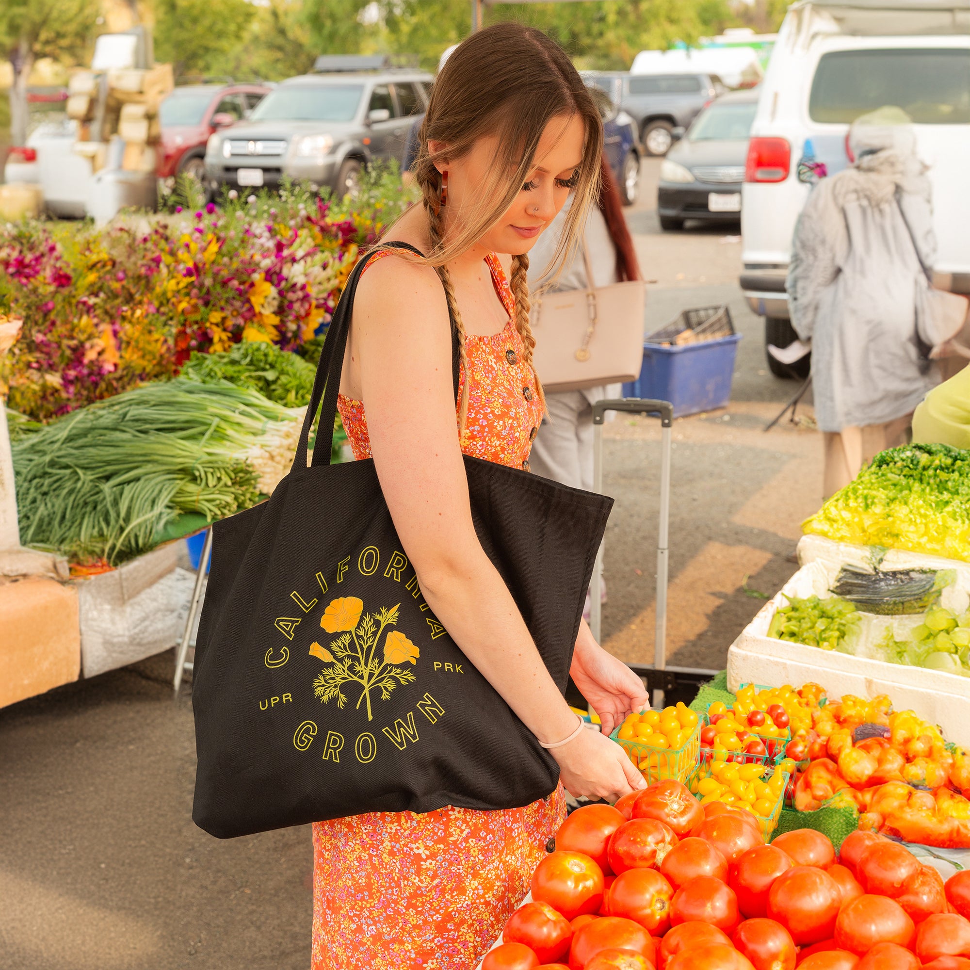 Woman wears a black California Grown Tote Bag from Upper Park Clothing at a farmers market in Chico, Ca