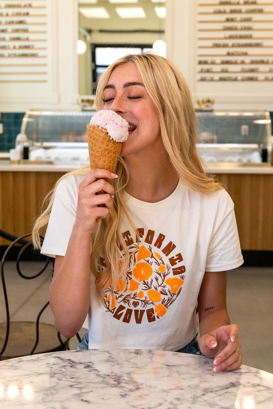 women sitting eating a ice cream cone while wearing a California Poppy Love Crop Tee from Upper Park Clothing