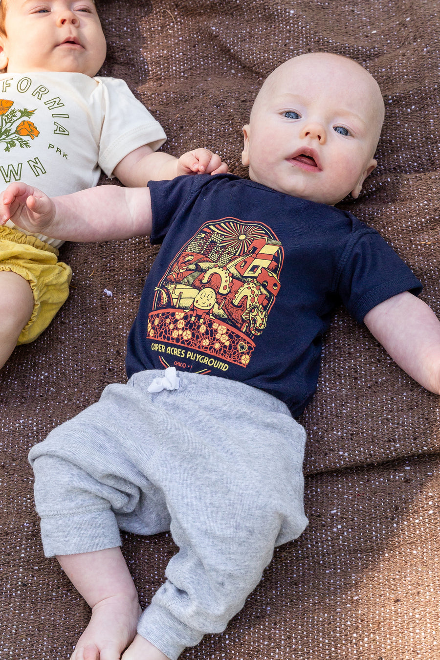 baby boy wearing a Caper Acres onesie laying on a brown blanket from Upper Park Clothing