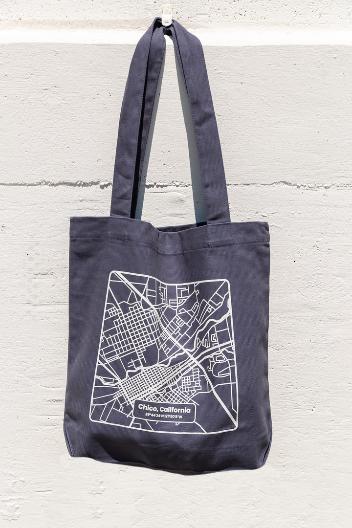 a blue Upper Park Clothing Chico Map tote bag hanging on a white wall