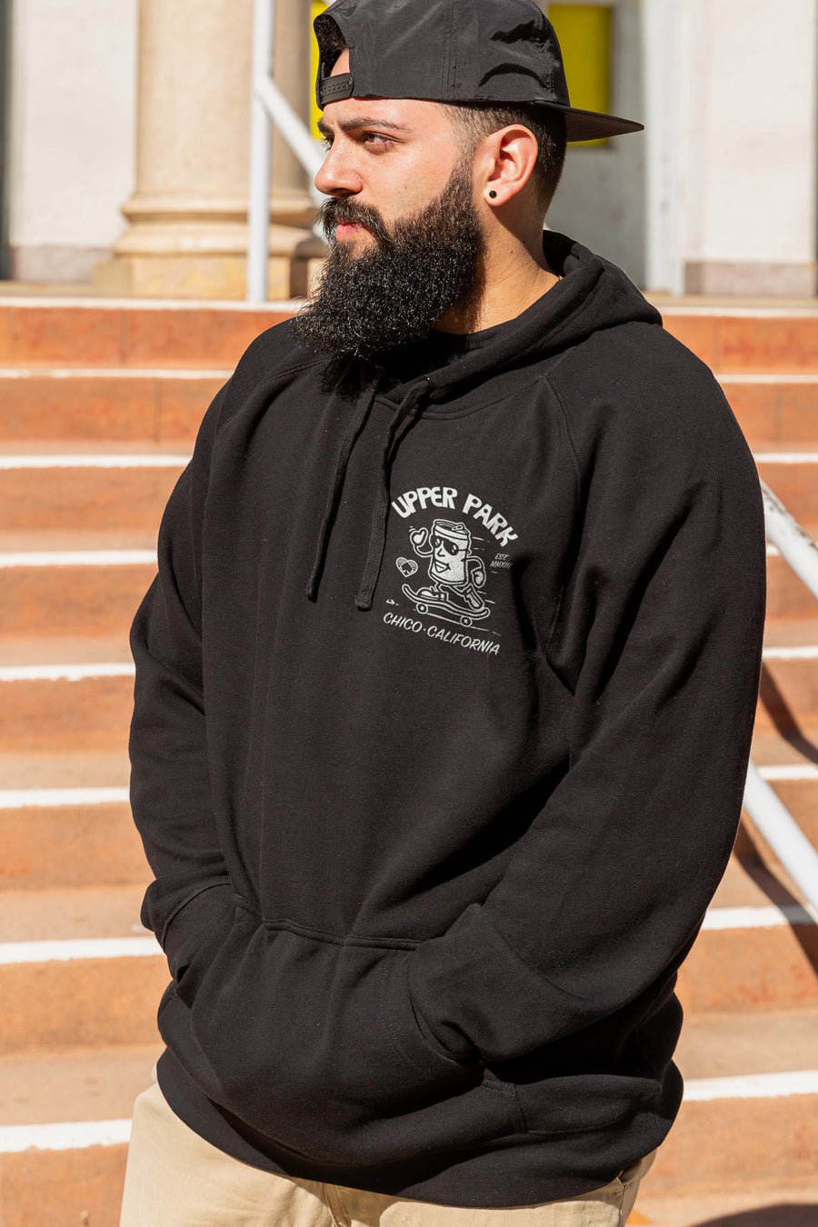 man standing in steps wearing a Corner Store Connoisseur hoodie from Upper Park Clothing