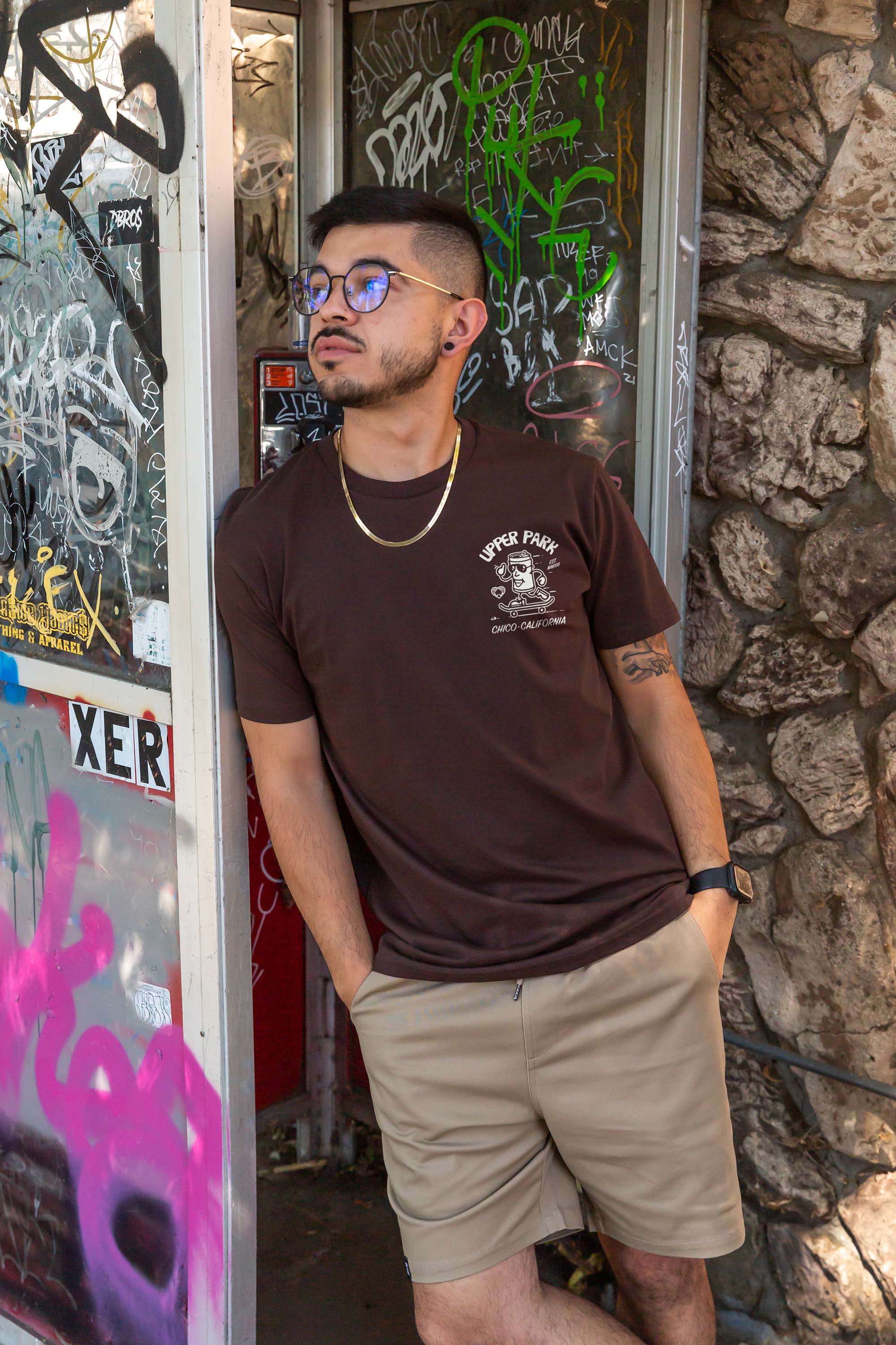 man leaning against a telephone booth wearing a Upper Park Clothing Corner Store Shirt