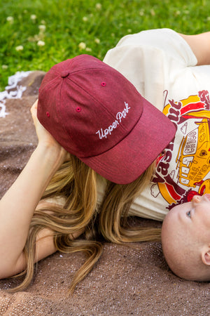 Mother and son laying on a Upper Park Clothing blanket wearing a performance hat while looking down at her son