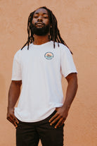 man standing in front of a pinkish wall wearing a Freshwater Floating Club shirt from Upper Park Clothing