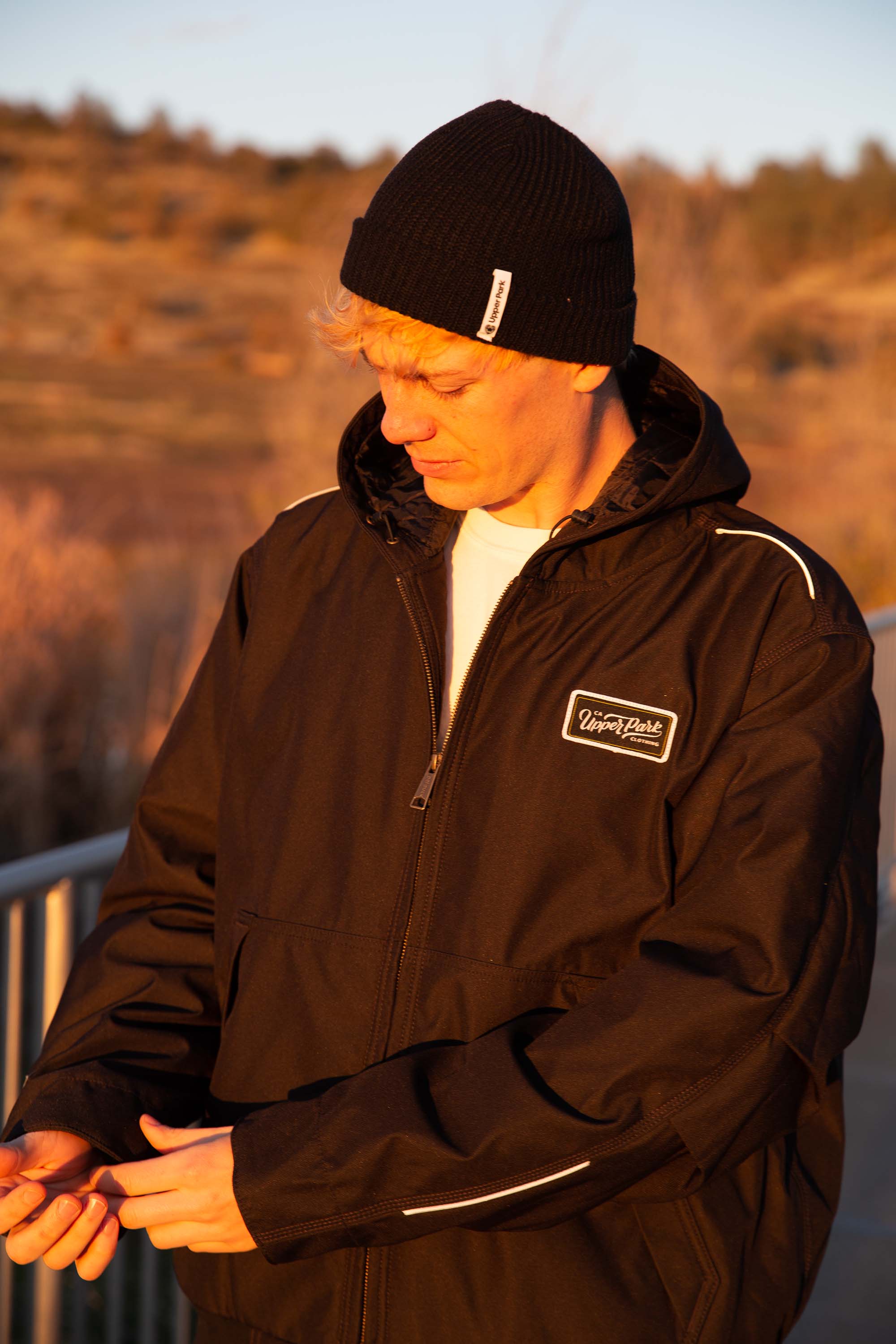 man leaning against a rail at Horseshoe Lake in Upper Bidwell Park wearing a workwear back from Upper Park Clothing