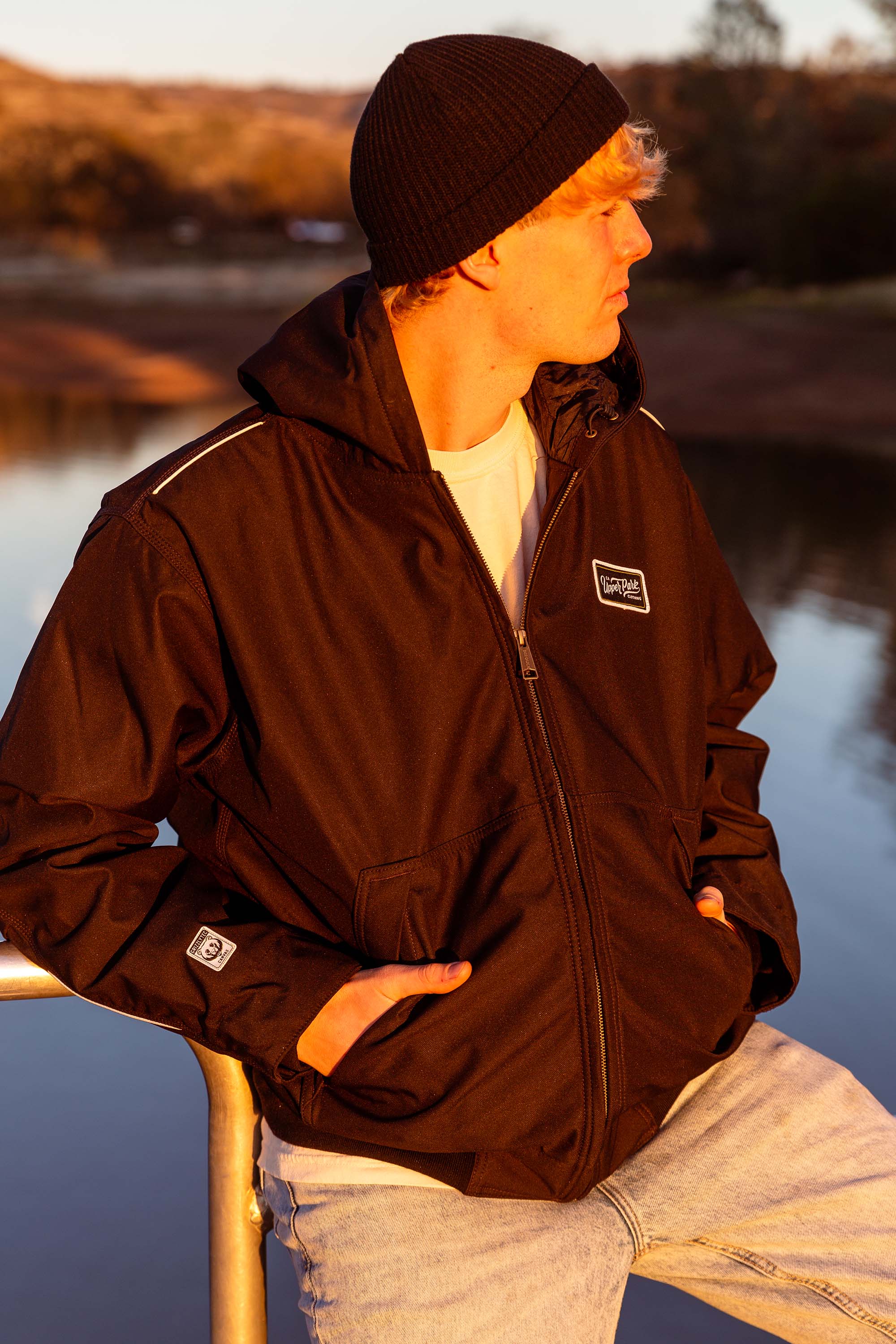 man leaning against a rail at Horseshoe Lake in Upper Bidwell Park wearing a workwear back from Upper Park Clothing