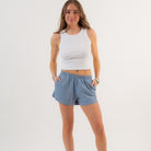 Woman wearing a white tank top and blue shorts on a plain background - Cotton Gym Shorts
