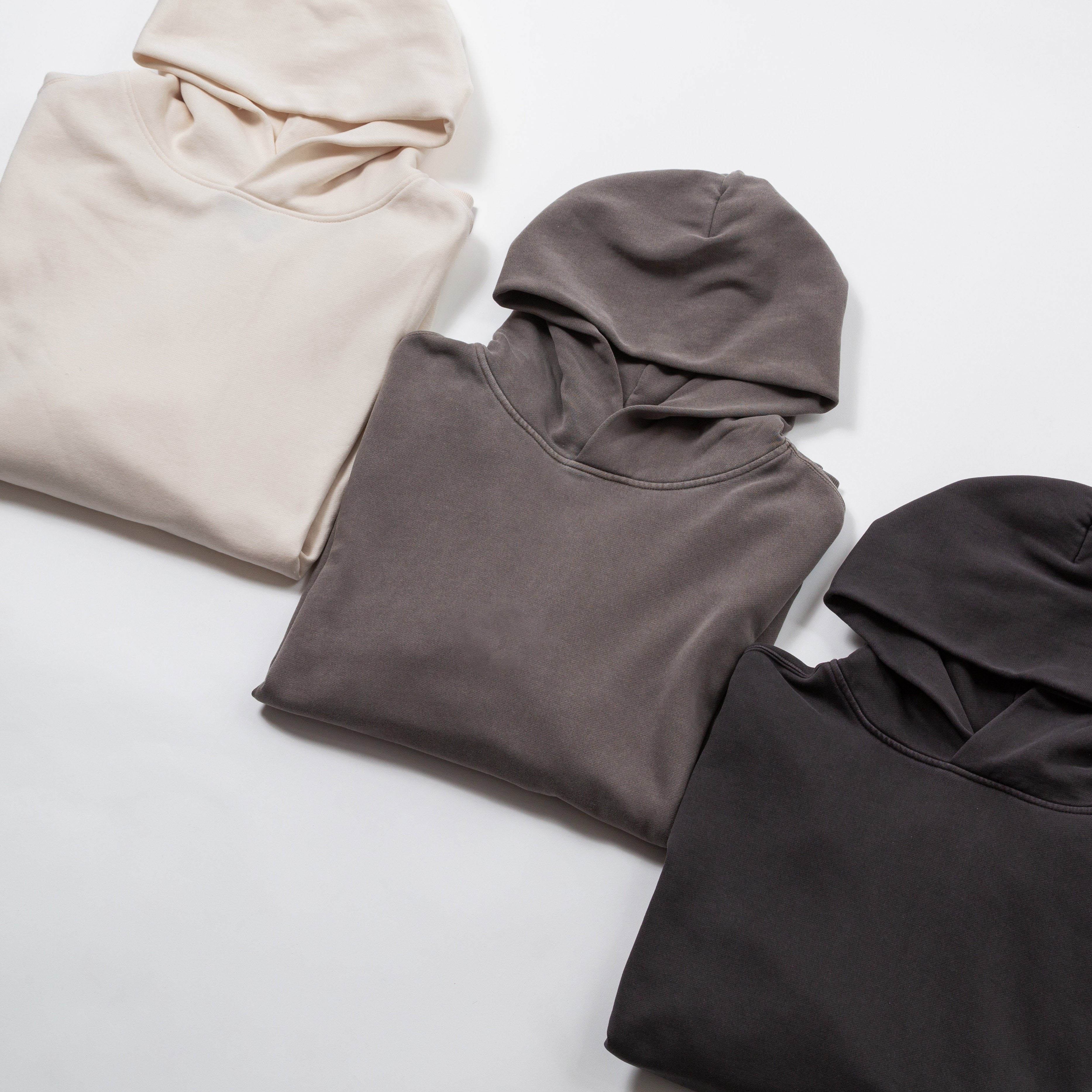 Relax oversize hoodie garment dyed - Three folded hoodies in beige, gray, and black on a light gray background