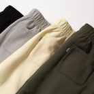Four pairs of pants in black, gray, yellow, and green on a light background - Upper Park Athletics Sweatpants Set