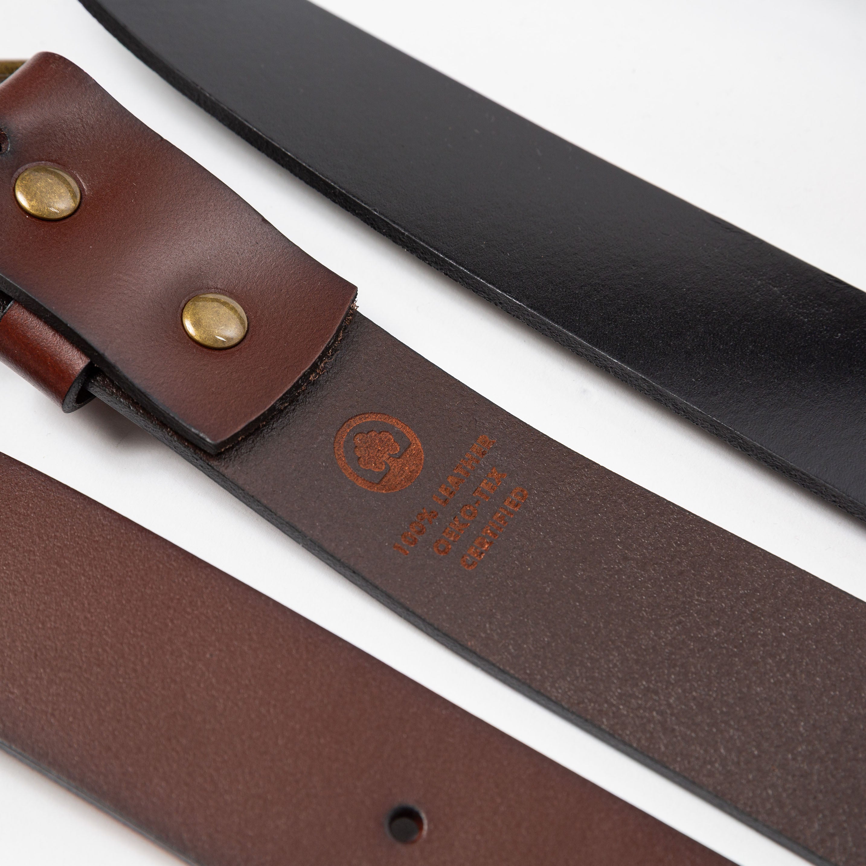 a close up of two leather belts showing the underside and top side textures with  an etching burned into the underside showing 100% leather - Upper Park basic leather belt