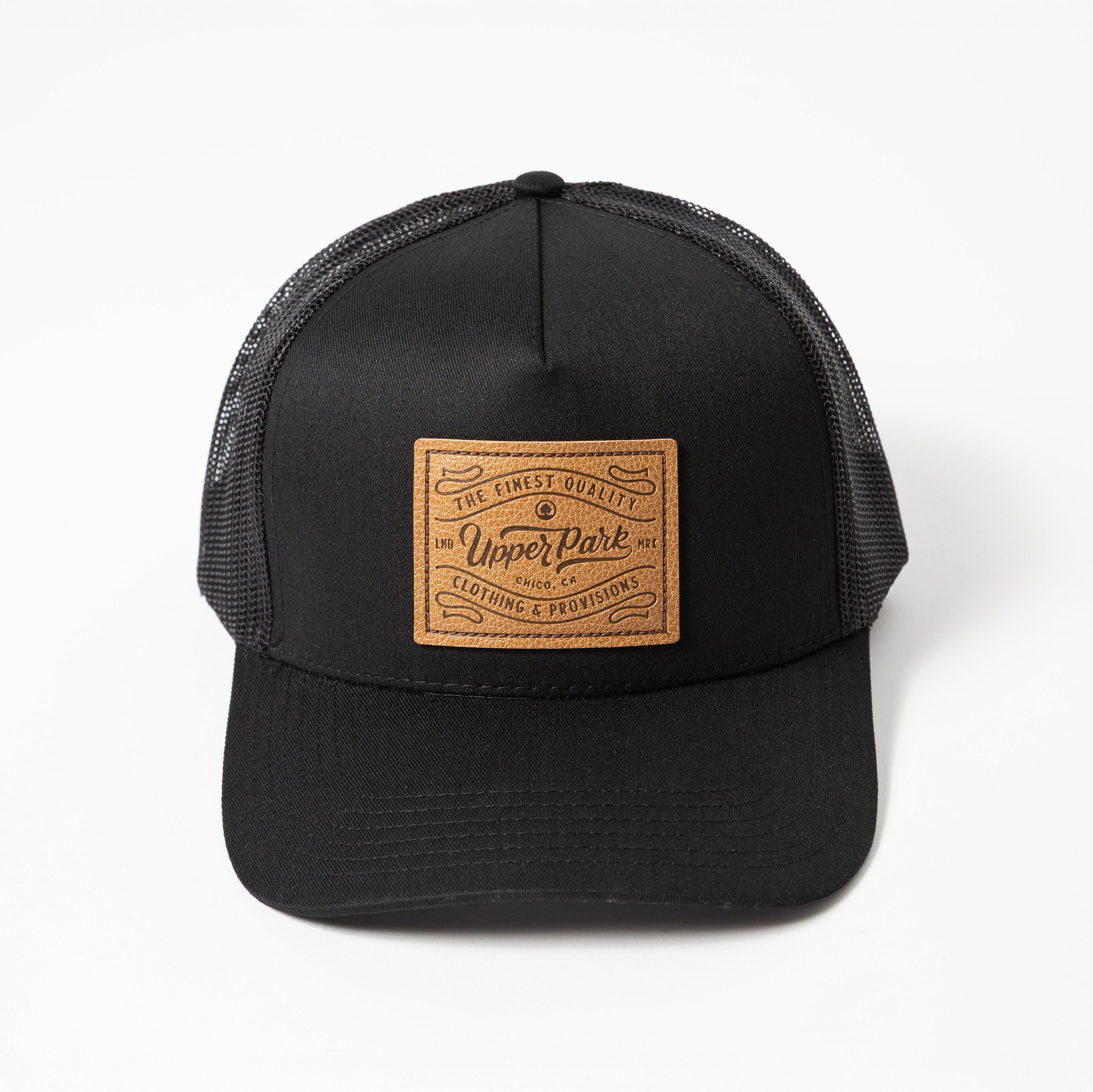 Upper Park Pro Label 5 Panel Trucker Hat - Black trucker cap with a leather patch on a white background