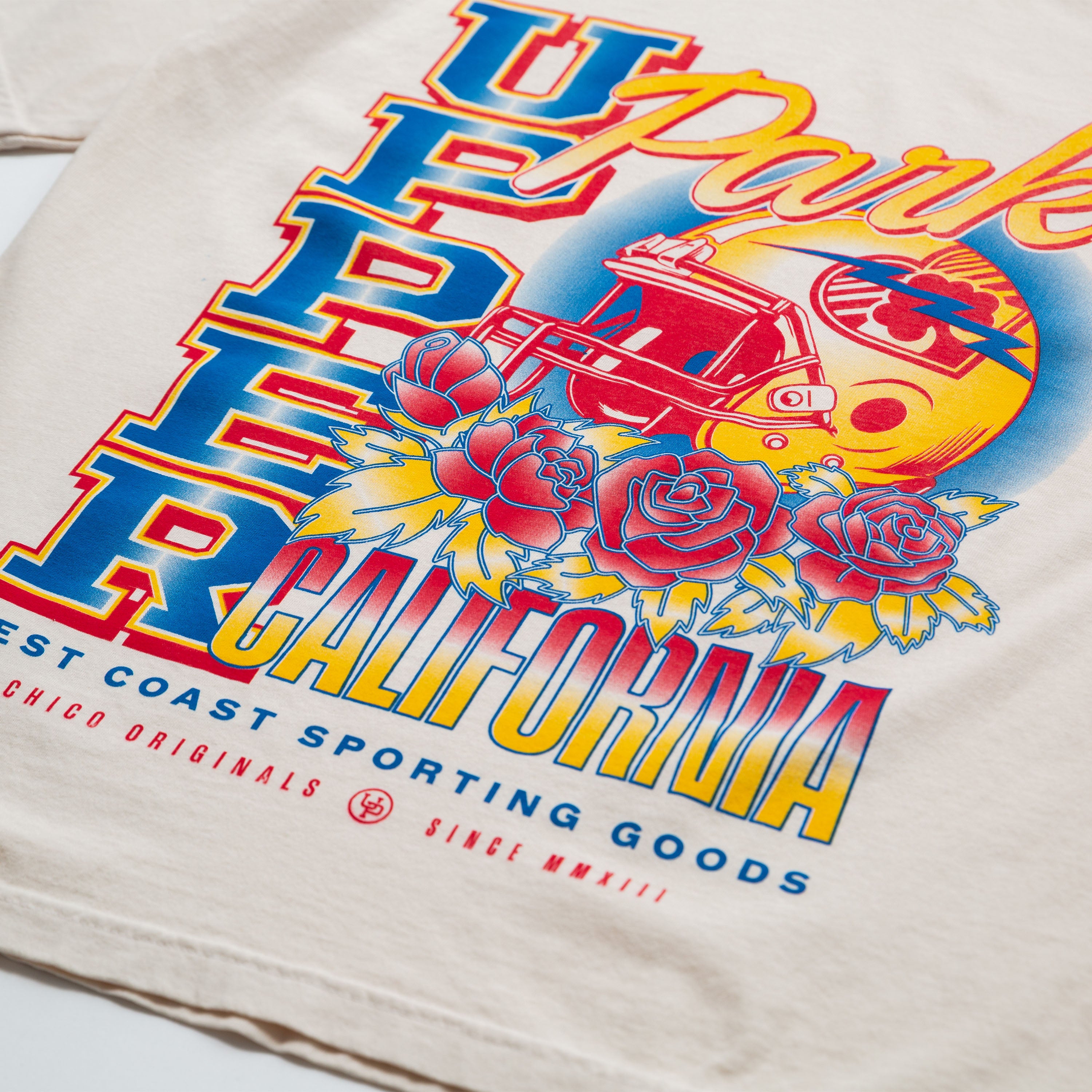 Upper Park Varsity Rose Football Tee - Beige sweatshirt with colorful graphic design featuring text and graphics on a white background