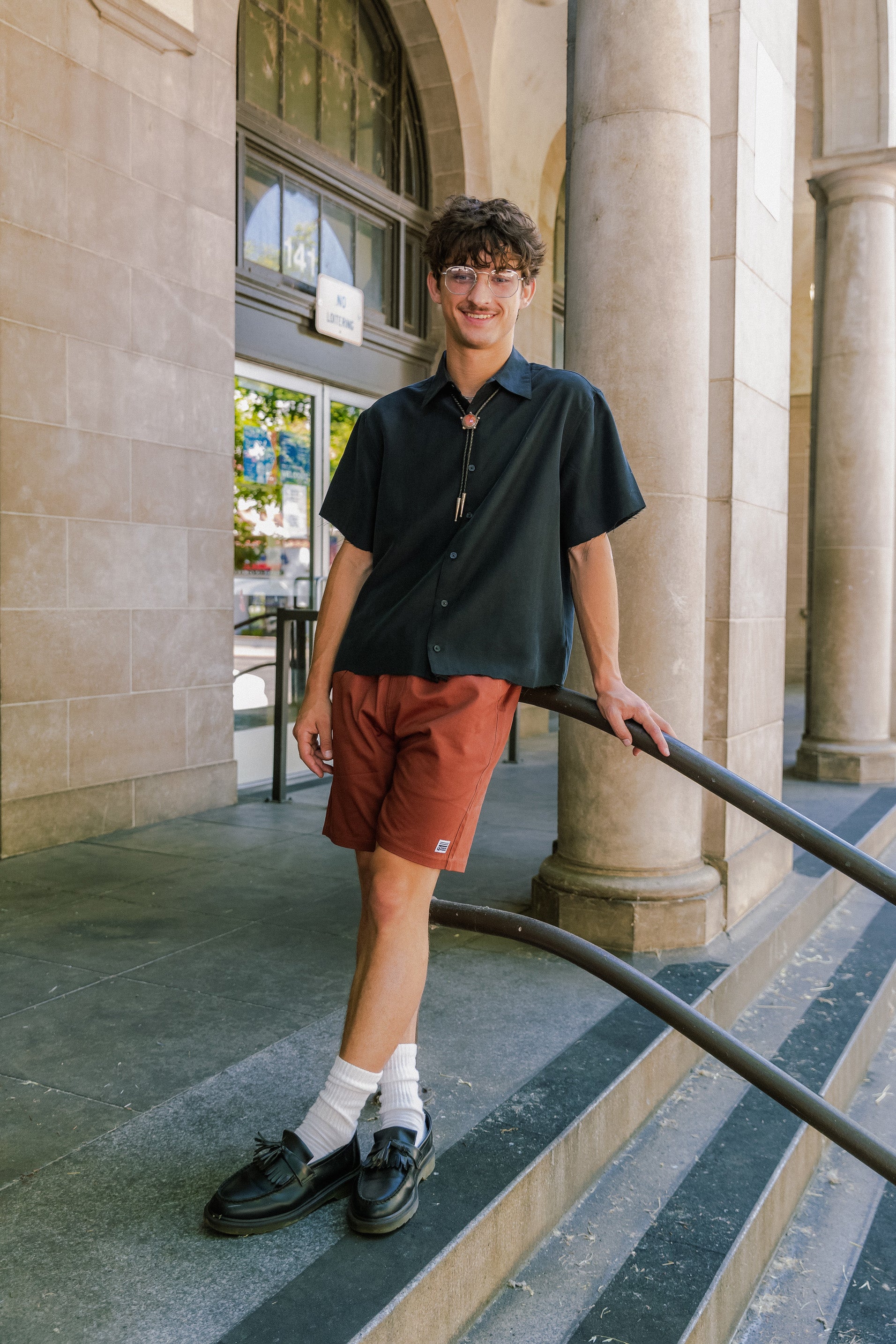 man standing on the stairs in front of the U.S Post Office in Downtown Chico wearing clay walk shorts from Upper Park Clothing