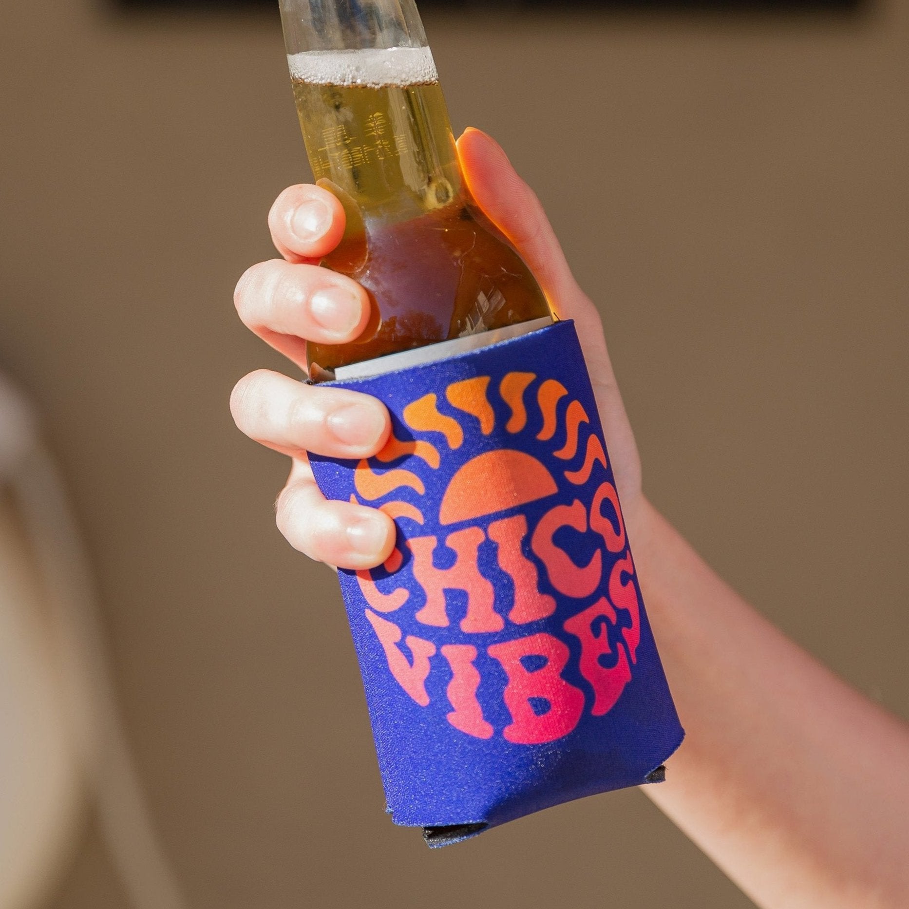 Hand holding a blue Chico Vibes Koolie Can Cooler from Upper Park Clothing - Chico, Ca