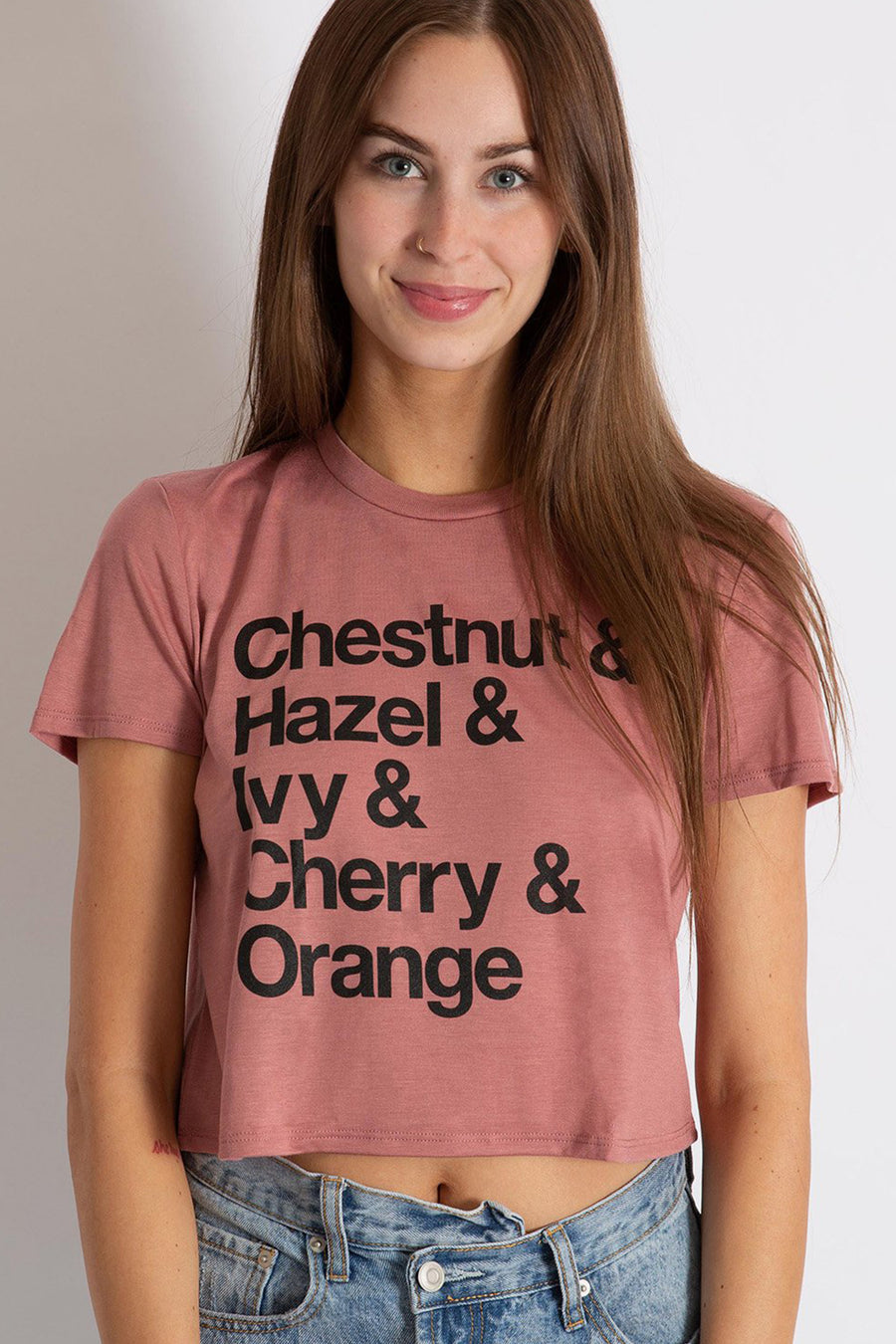 women in a photography studio modeling a mauve colored crop tee with a graphic of the streets that spell out Chico from Upper Park Clothing